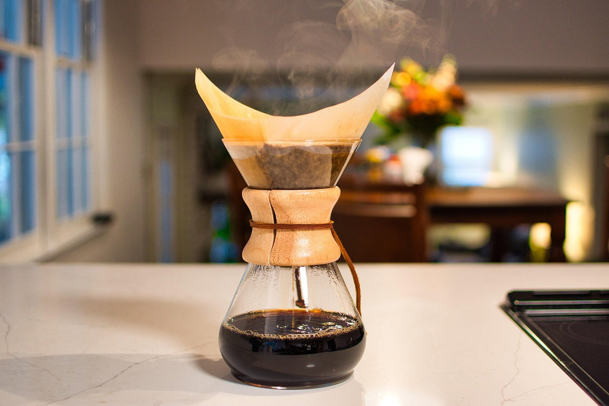 A glass pour-over brewer on a bright kitchen counter